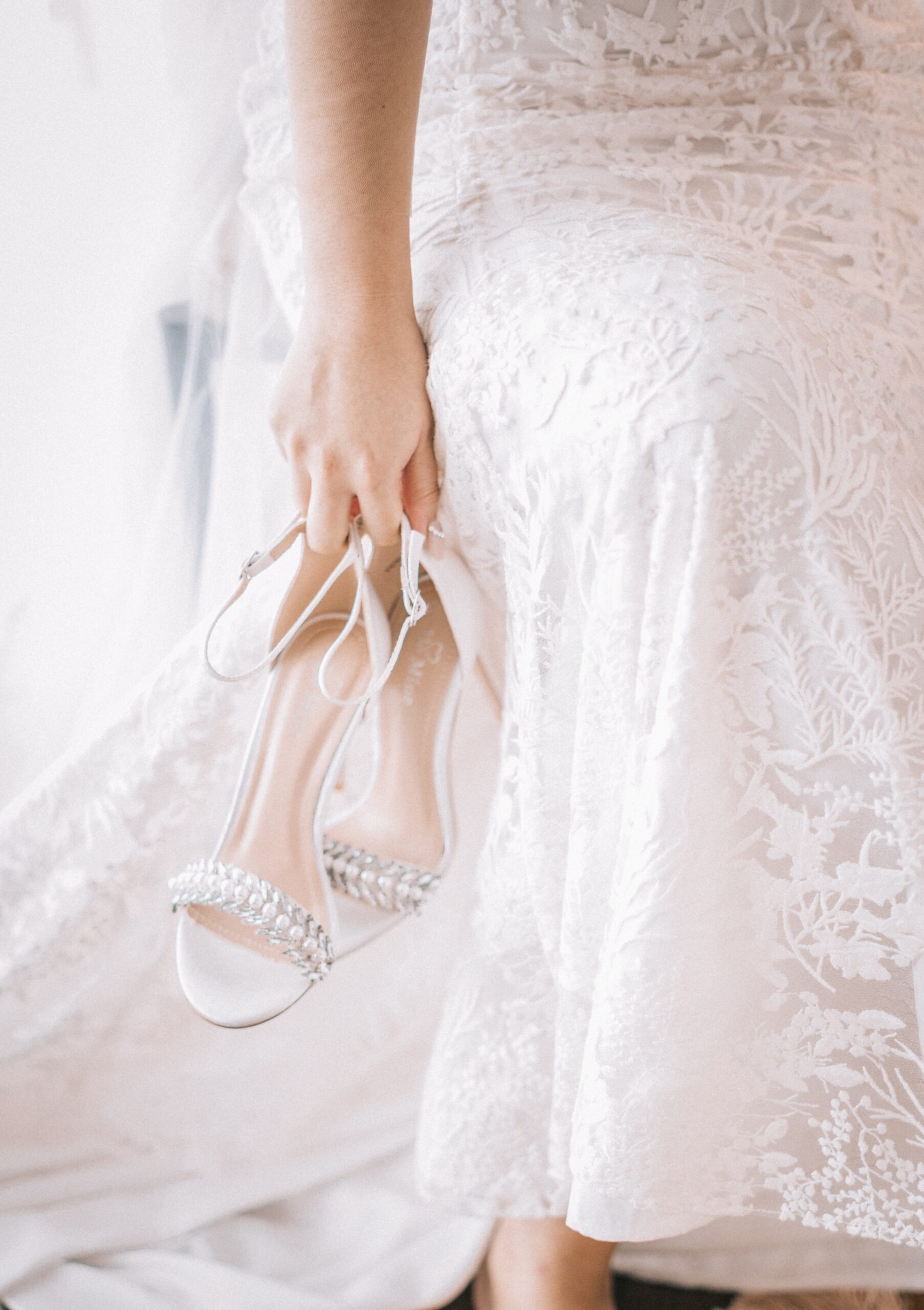 Bride in gown holding her wedding shoes on her wedding day